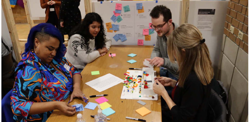 Four Participants at table manipulating legos and writing on post-its