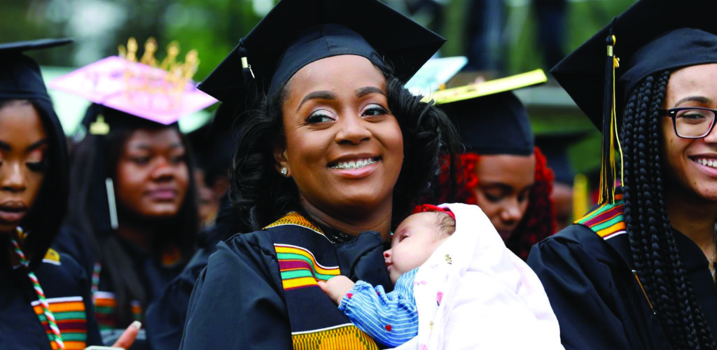 Woman in cap and gown holding baby