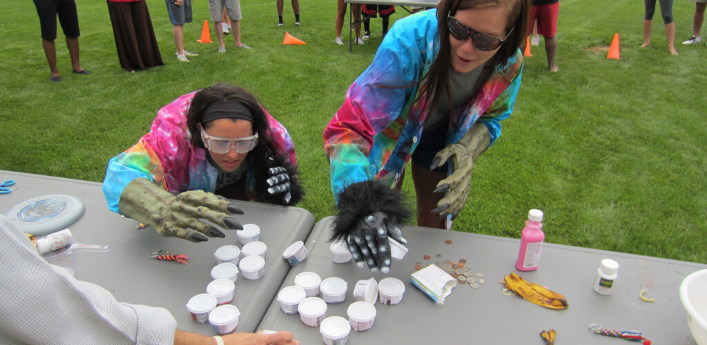 Students with monster costume gloves on participating in activity on table